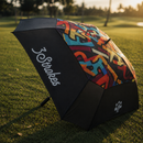 Colorful umbrella with '3 Strokes' branding on a grassy field