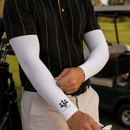 Person wearing white arm sleeves with a logo, holding a golf club on a golf course.