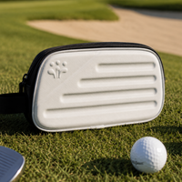 White golf bag with black strap on a golf course with golf balls and club.